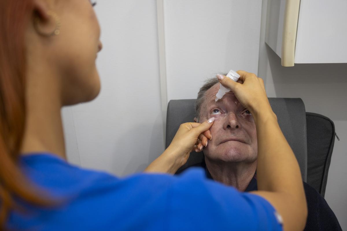Clinician applying eye drops to an older patient during an ophthalmology examination